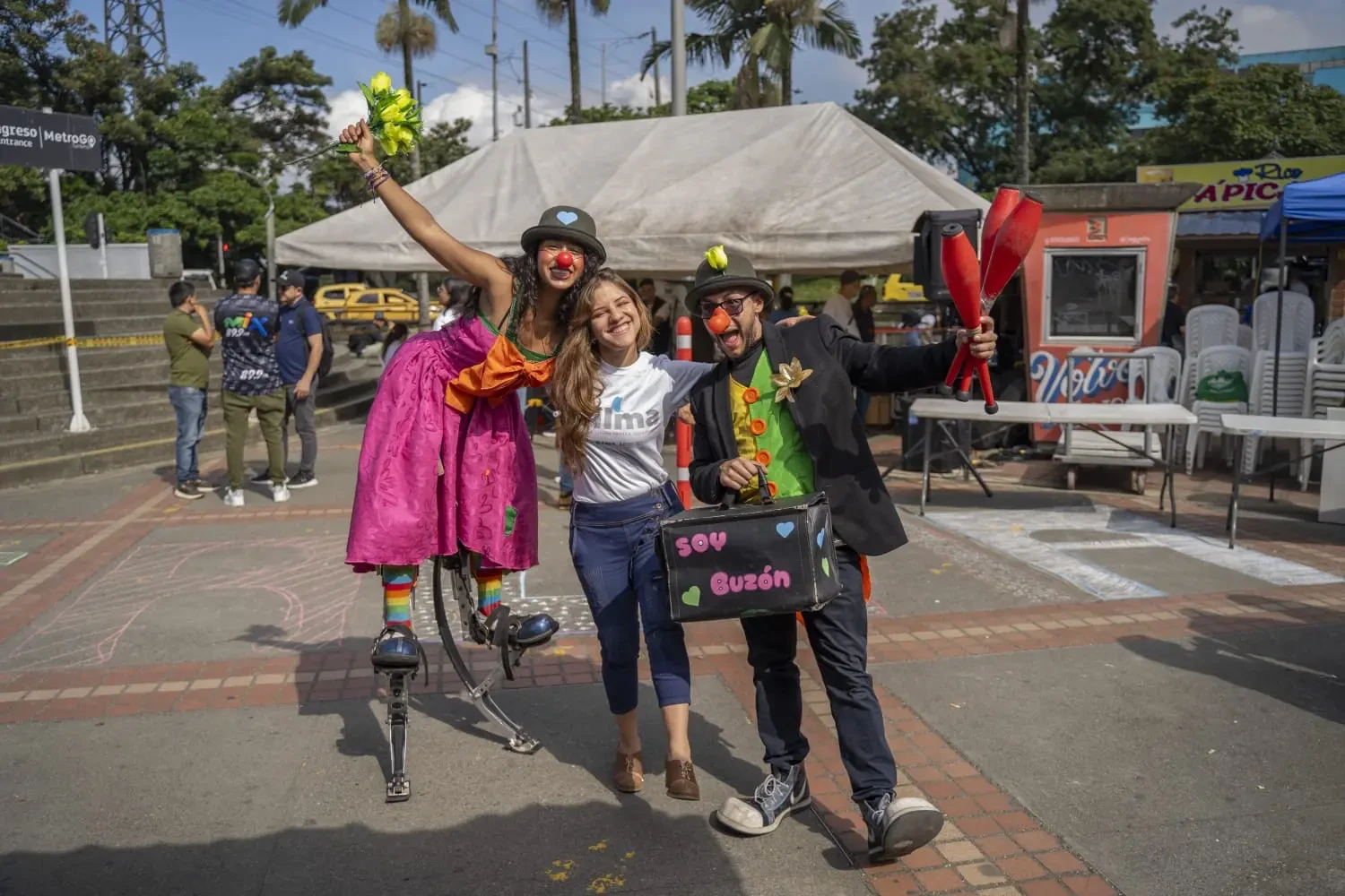 Una profesora de la IU Digital, un payaso del evento 'Calma que transforma' y otro payaso mujer montada en sancos durante una actividad del evento en Antioquia.